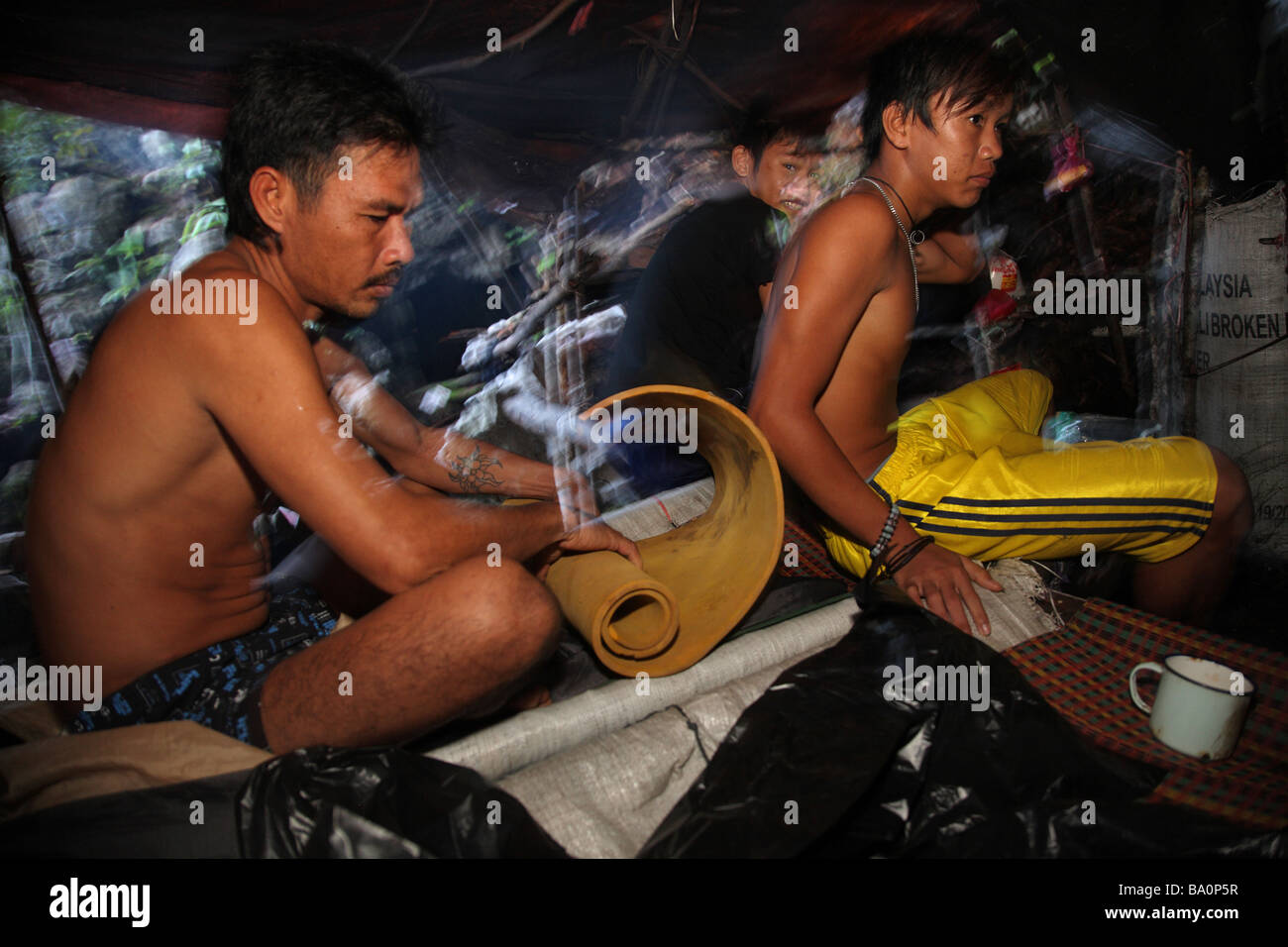 Porters gather their belongings ready to leave a jungle camp in Borneo Stock Photo