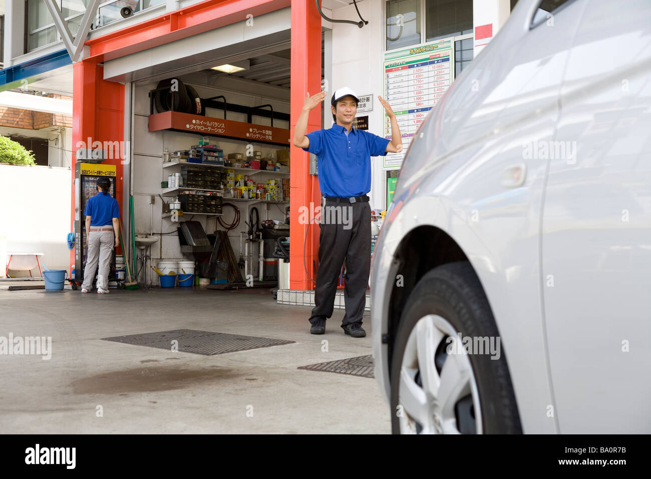 Gas station clerk guiding car Stock Photo - Alamy