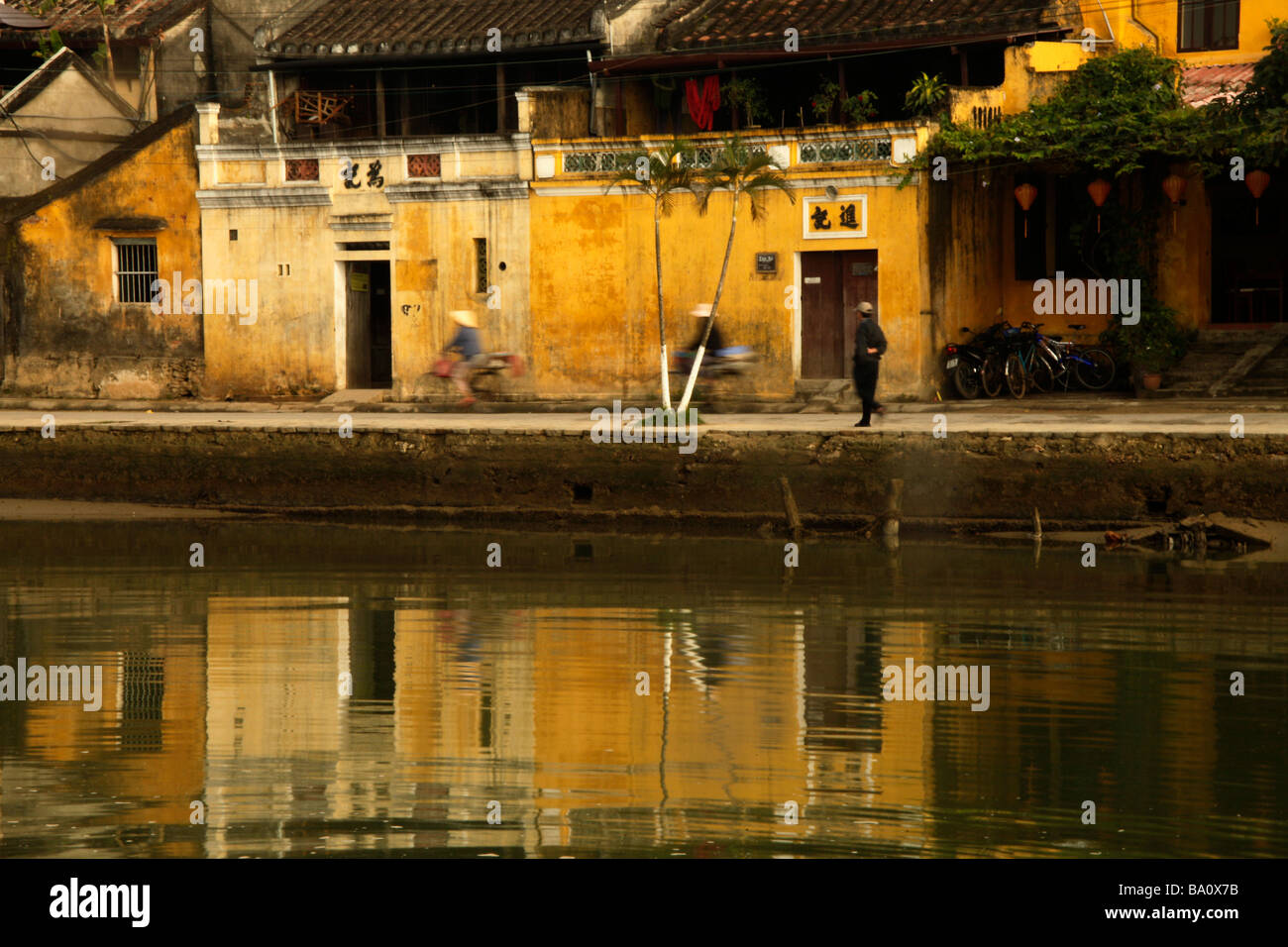 cyclists on the promenade at the Thu Bon River in Hoi An Vietnam Stock Photo