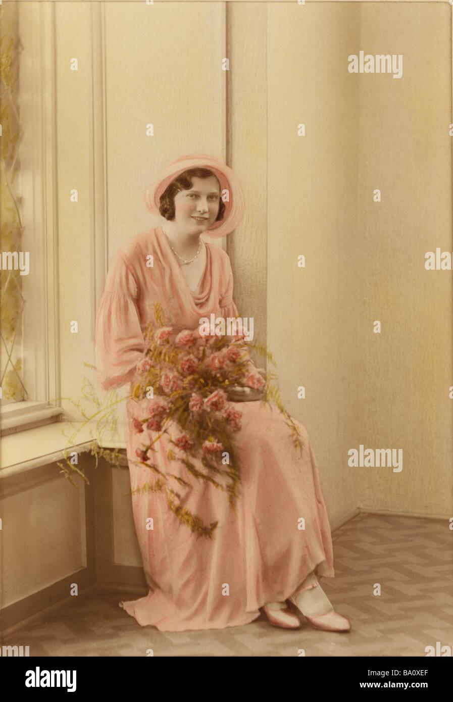 Early 1900's tinted photo of young bride holding a bouquet of pink flowers, twenties 20's, U.K. Stock Photo