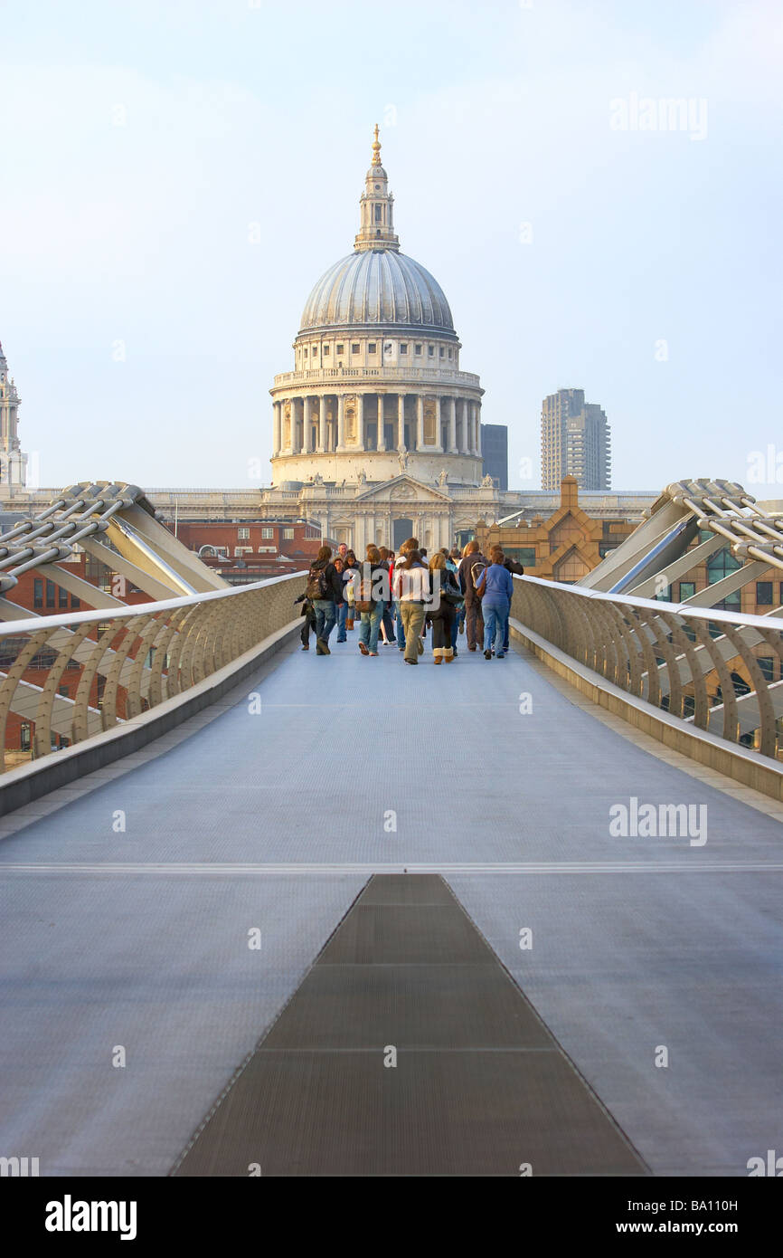Tourists cross the London Millennium bridge and walk towards St Paul's Cathedral in the city of london uk. Stock Photo