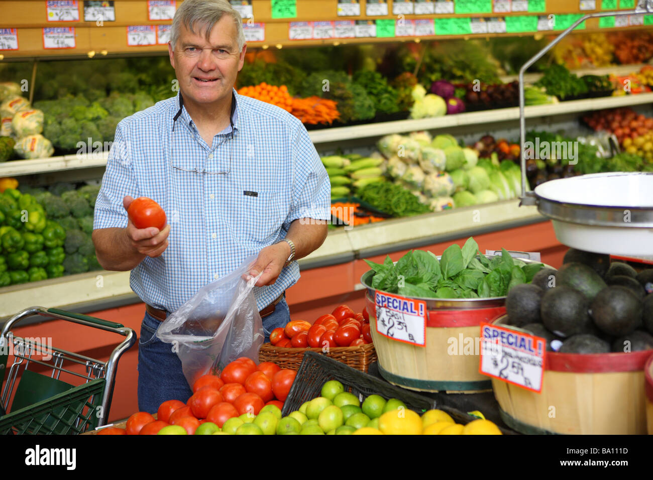 Senior man in grocery store picking out produce Stock Photo