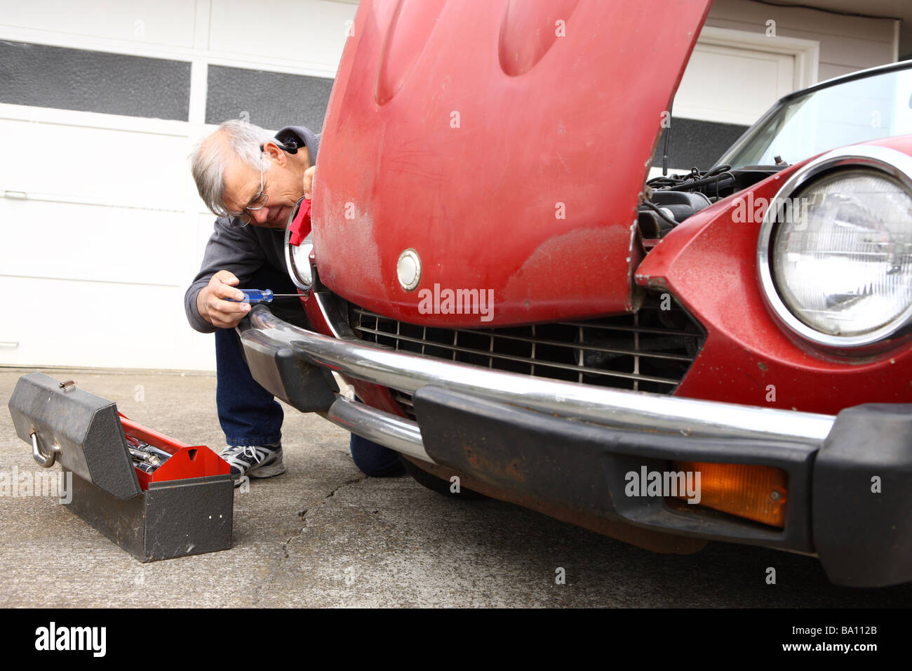 Senior man fixing classic car Stock Photo