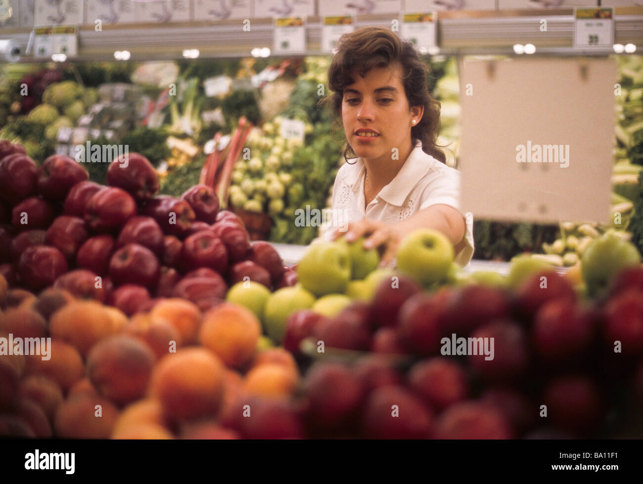 Hispanic  woman choose select pick apple fruit store grocery market food buy purchase Stock Photo