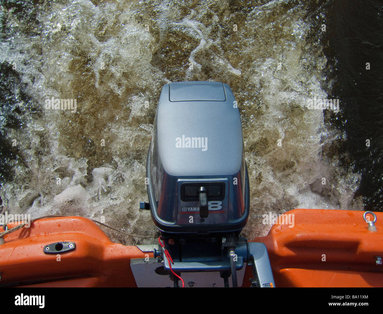 outboard motor engine on speedboat, in water showing wash which causes damage to riverbank Stock Photo