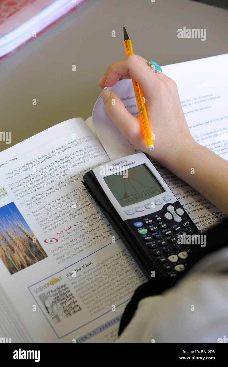 Close-up of student hands with scientific calculator, maths book and pen Stock Photo