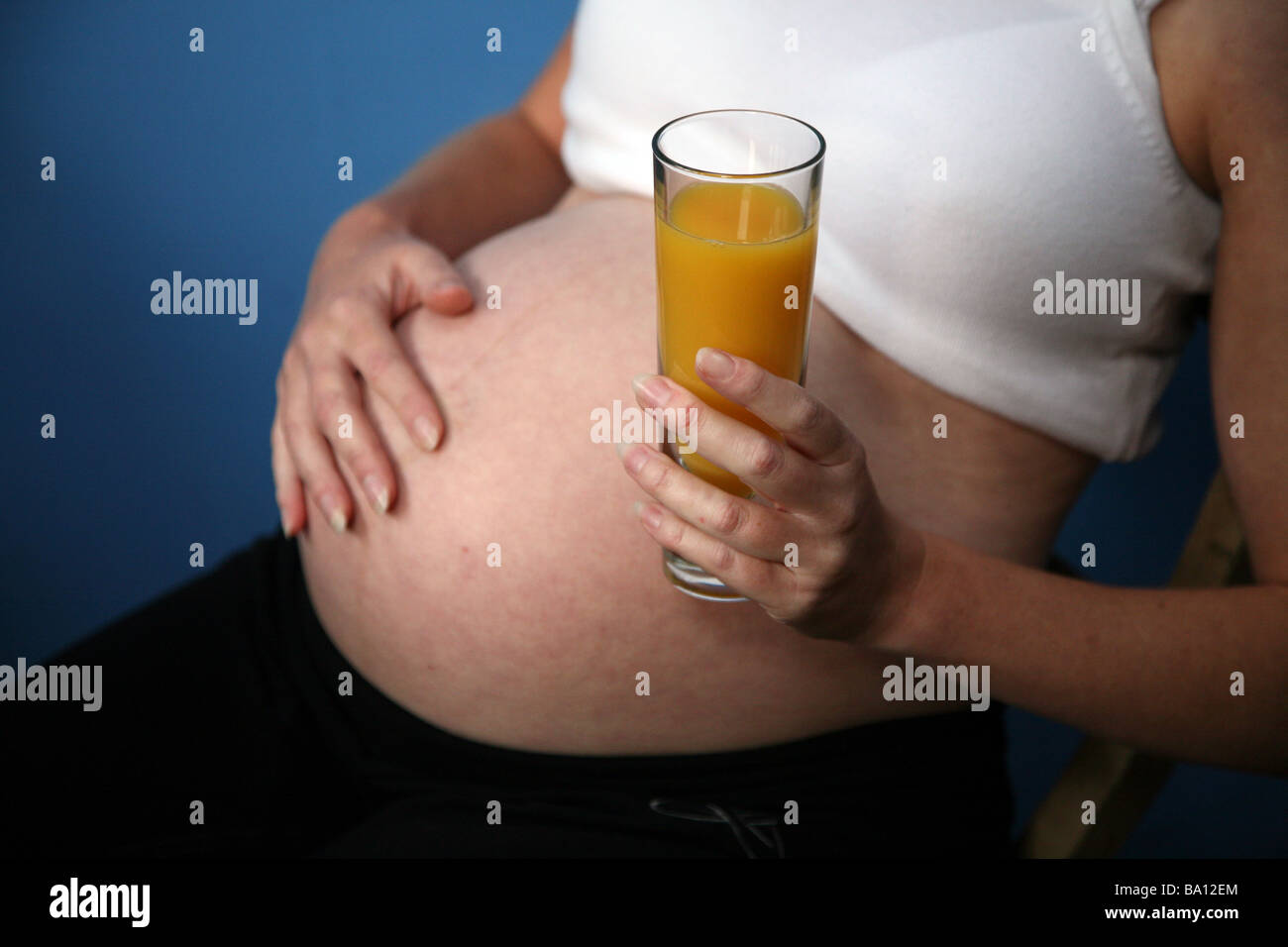 A pregnant woman with a glass of orange juice Stock Photo - Alamy