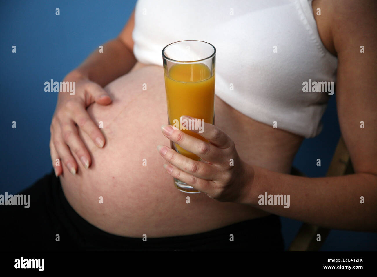 A pregnant woman with a glass of orange juice Stock Photo - Alamy