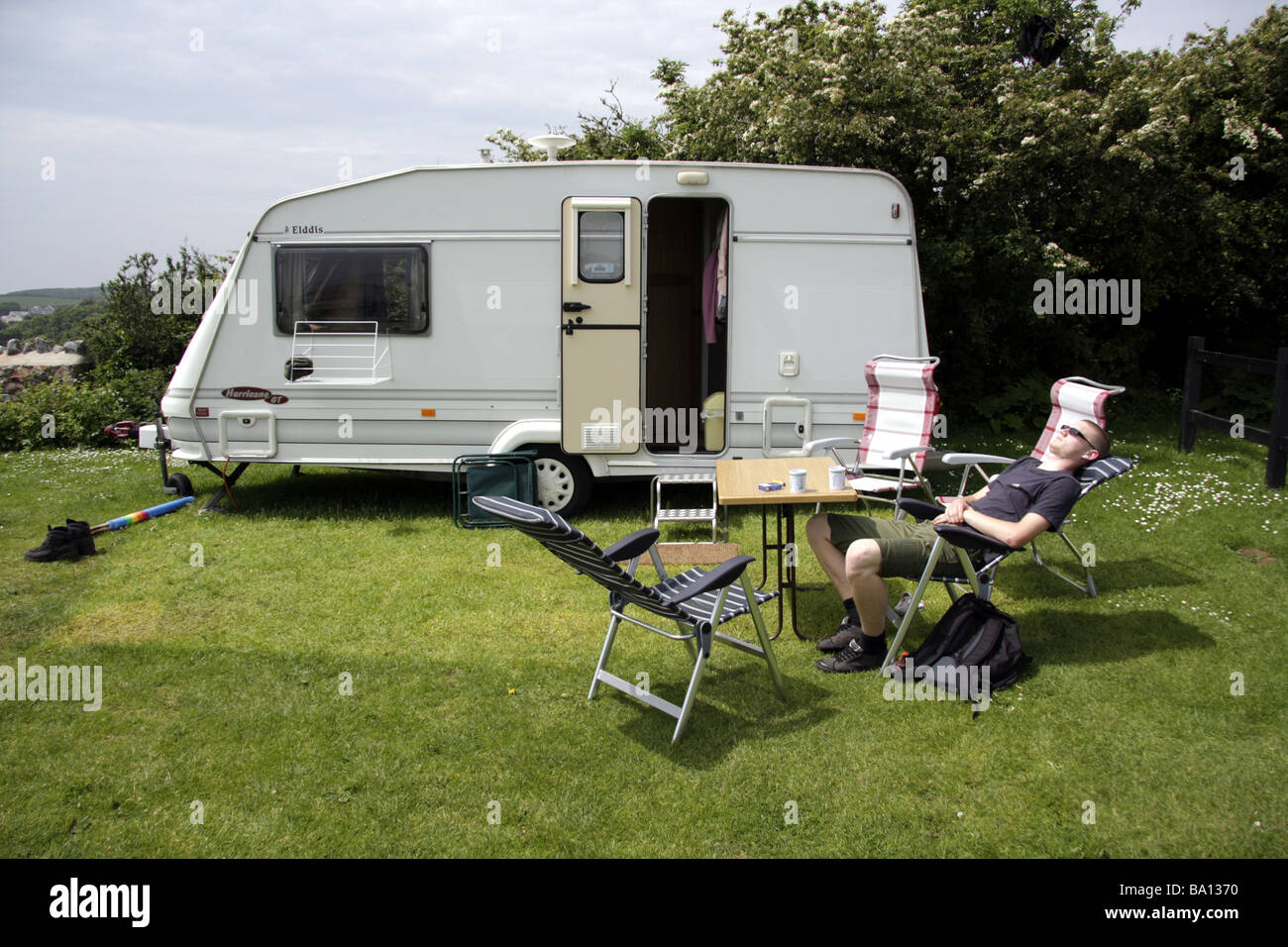 A teenage boy relaxing in the sunshine outside a touring caravan at a ...