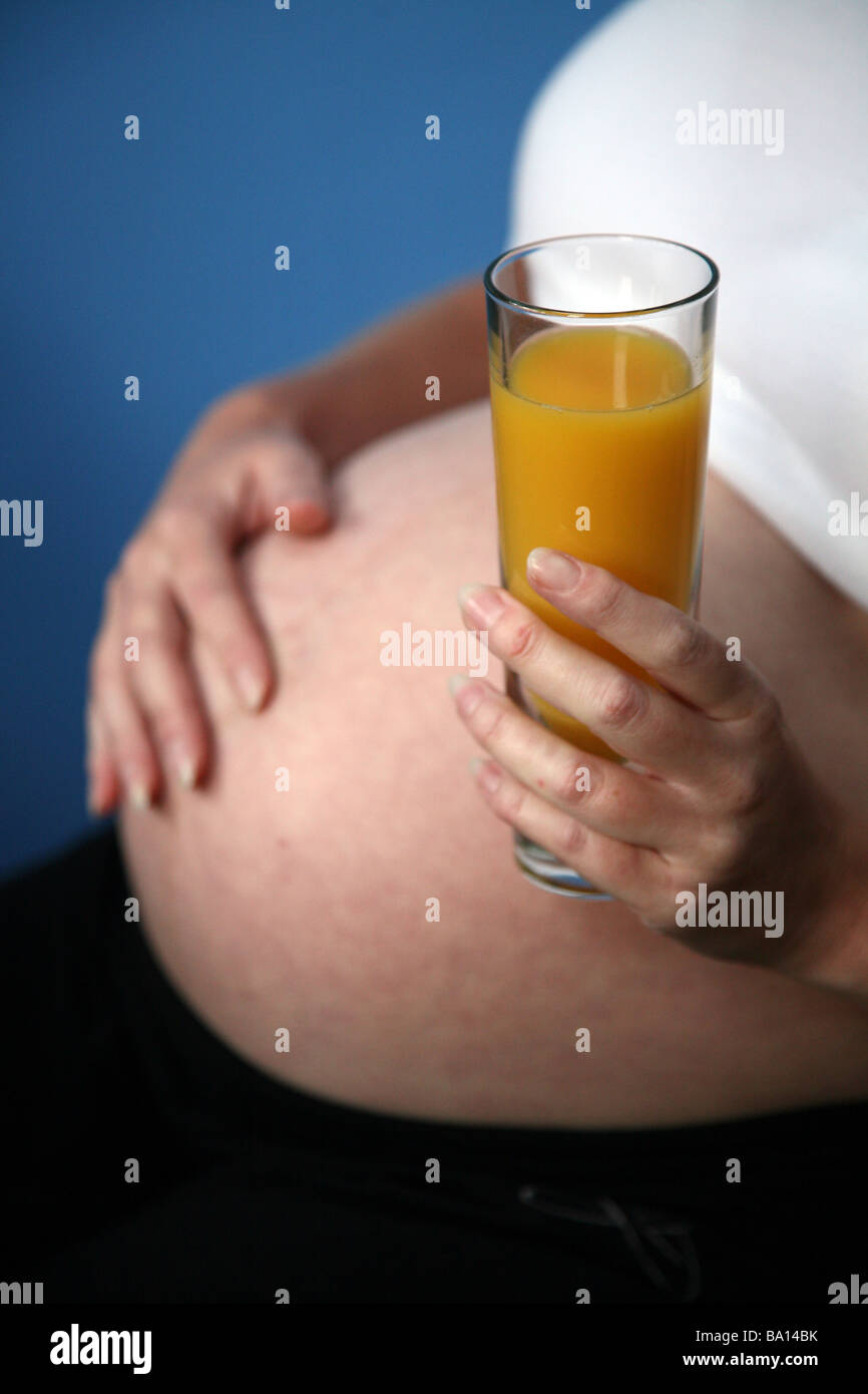 A pregnant woman with a glass of orange juice Stock Photo - Alamy