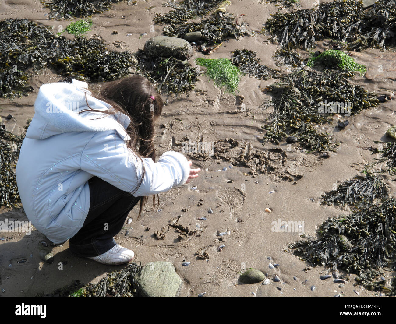 Little girl writing help in sand Stock Photo Alamy