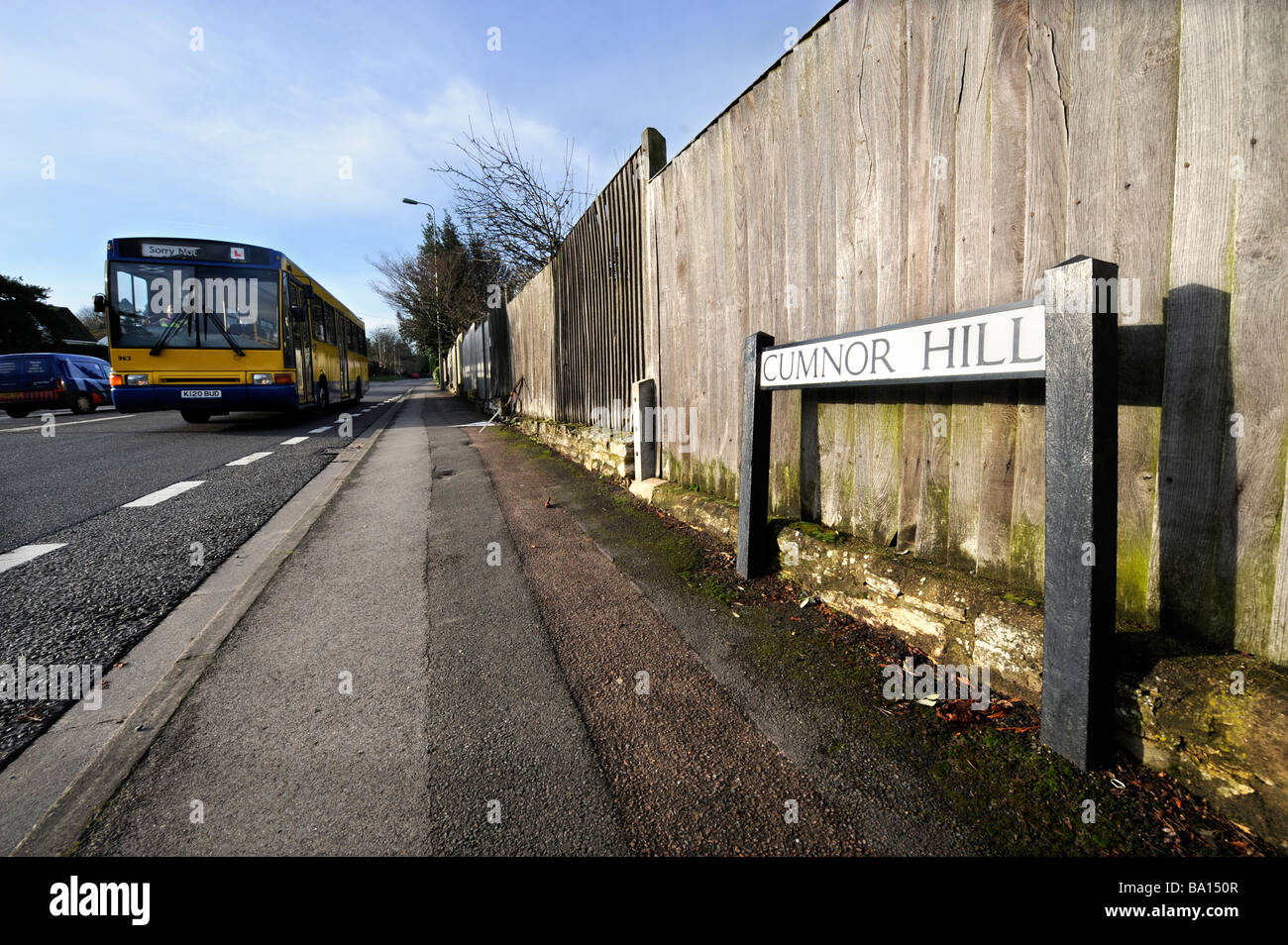 A BUS WITH A DRIVER UNDER INSTRUCTION PASSES A ROADSIGN AT CUMNOR HILL