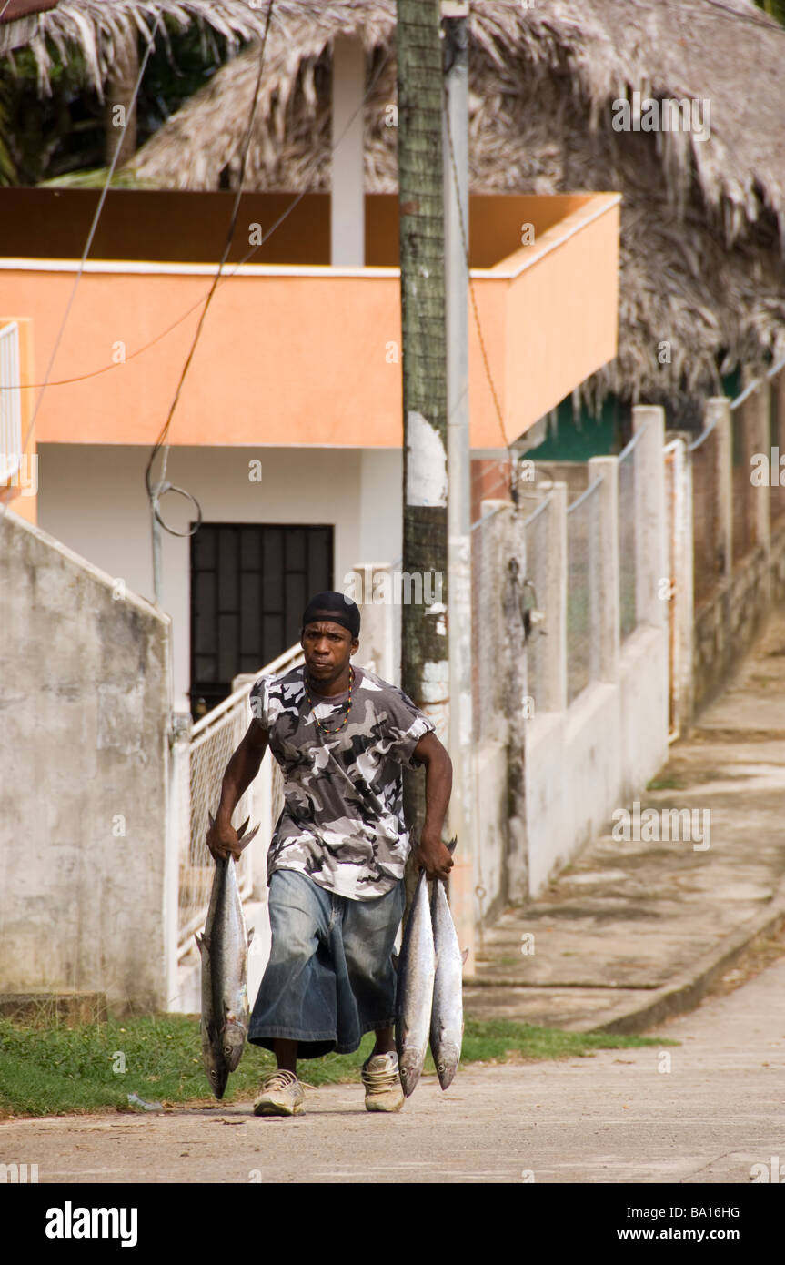 Garifuna boy carrying freshly caught fish in a street in Livingston, Guatemala Stock Photo