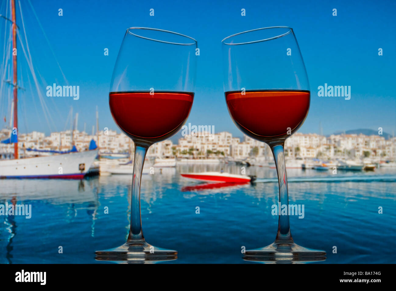 PUERTO BANUS MARBELLA FUN SPAIN HOLIDAY CHEERS rose wine glasses lean towards each other speedboat & Puerto Banus Marbella behind Costa del Sol Spain Stock Photo