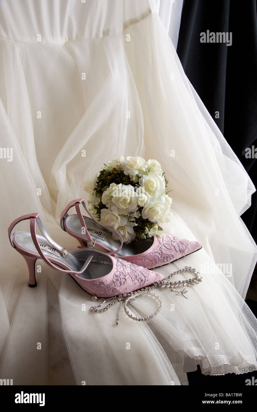 Bride's white wedding gown petticoat, pink embroidered shoes, white bouquet posy and jewellery Stock Photo