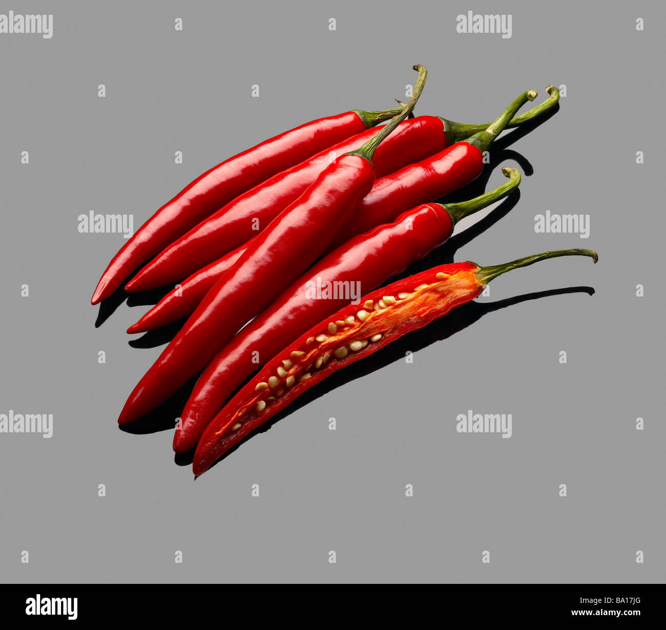 fresh red chili peppers over grey reflective surface Stock Photo