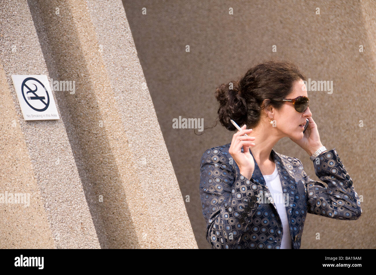 Business woman smoking in front an none smoking sign Stock Photo