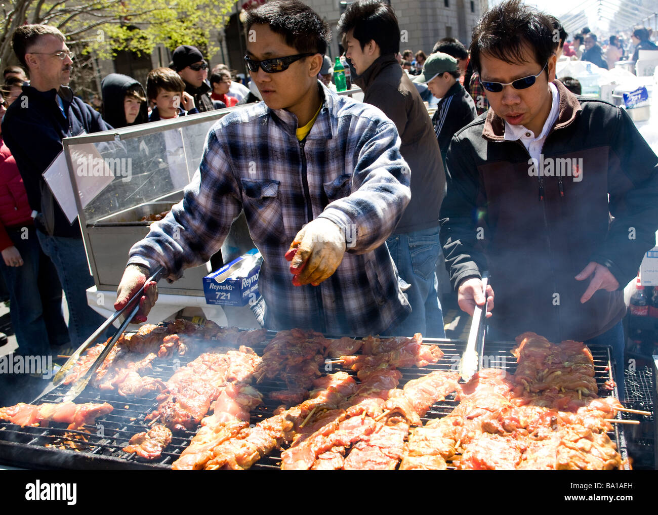 Asian cooks tending barbecue at an outdoor festival - USA Stock Photo