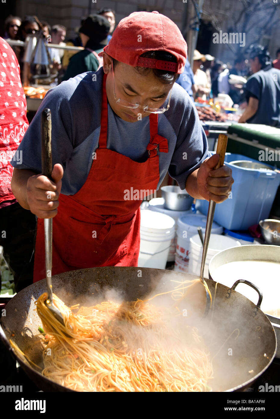 Asian man cooking noodles at outdoor street festival USA Stock Photo