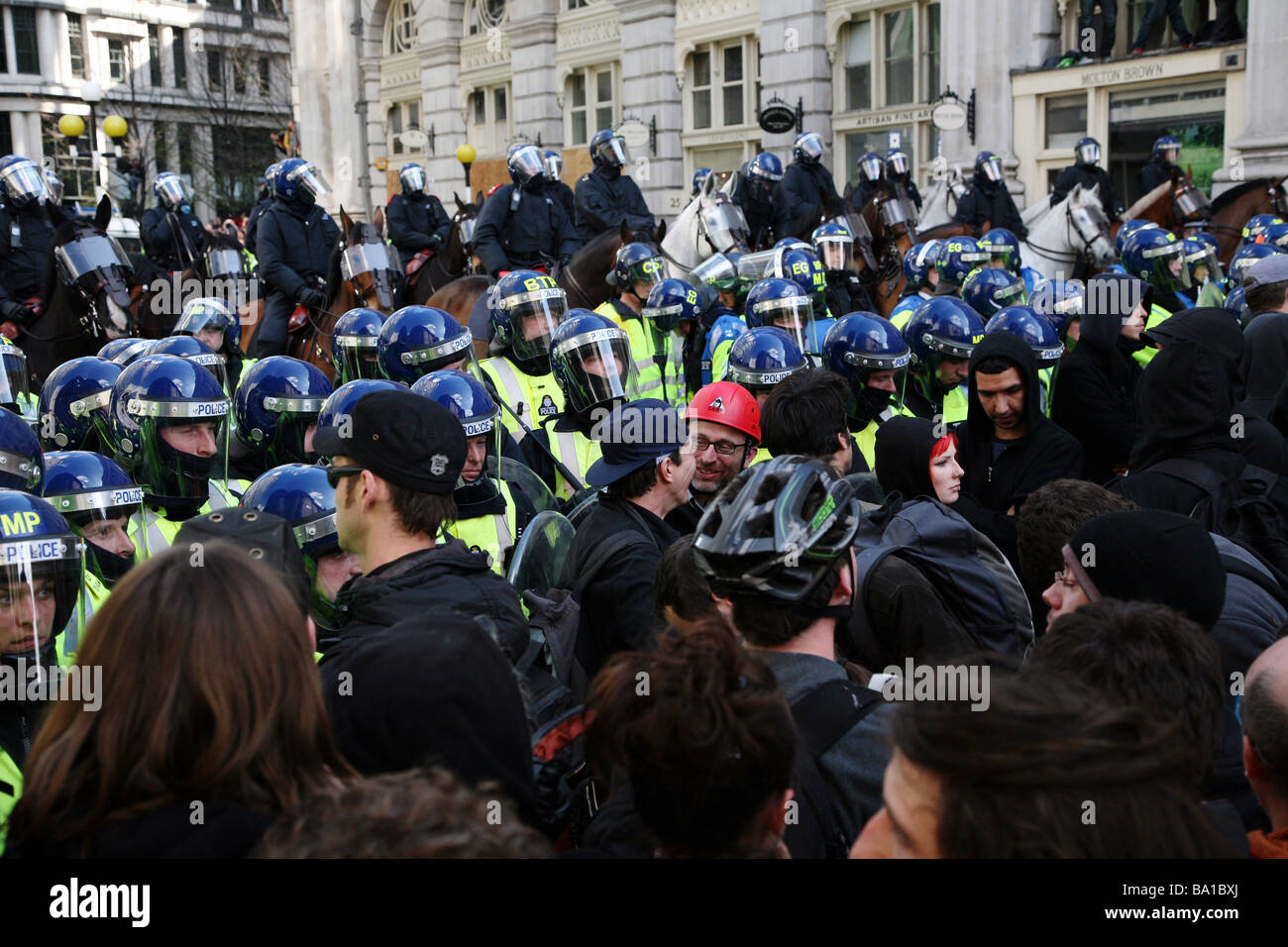 Riot police hold back protestors at the G20 protests in London Stock Photo
