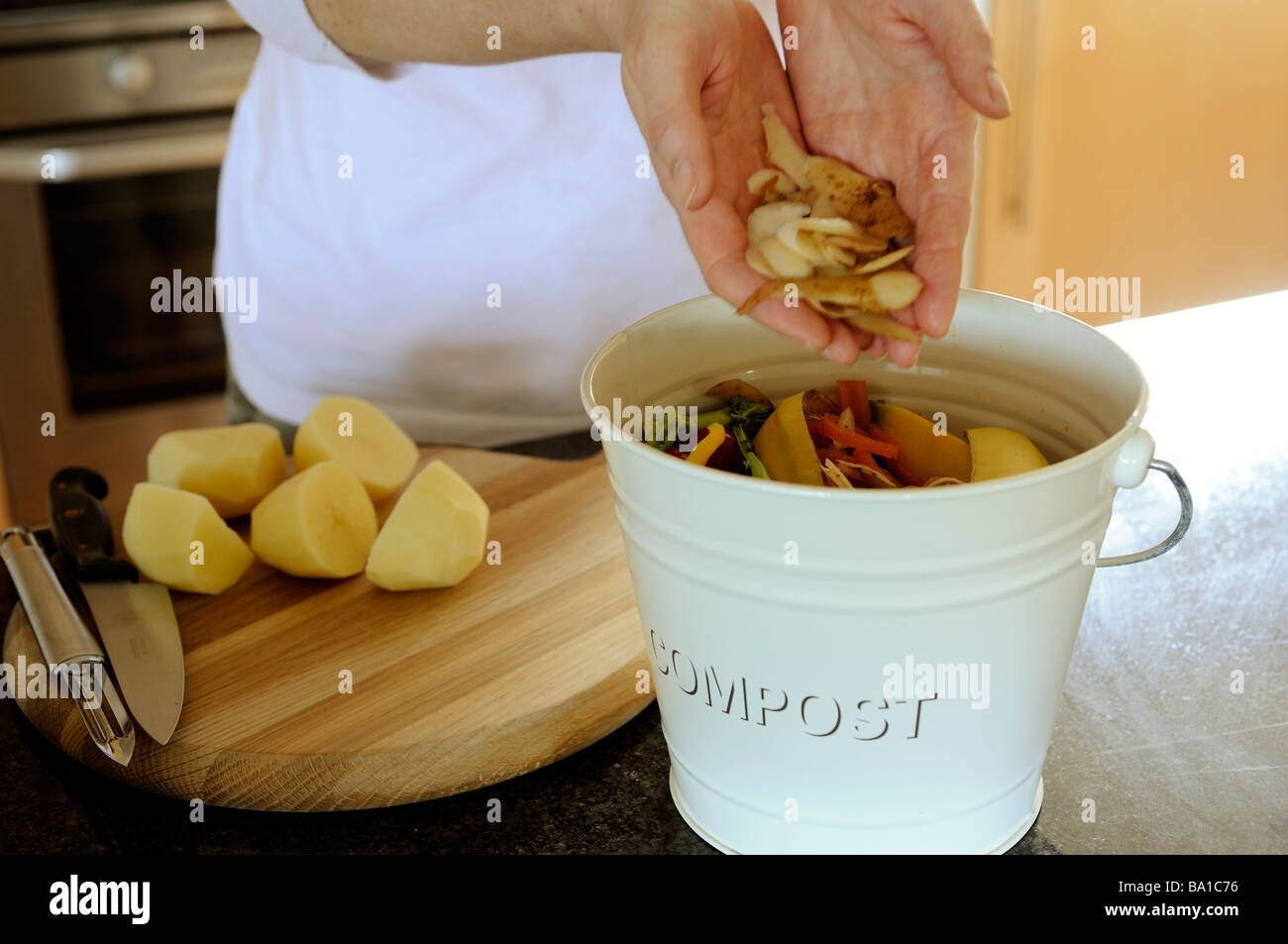 Woman putting potato peelings in compost bin Stock Photo Alamy