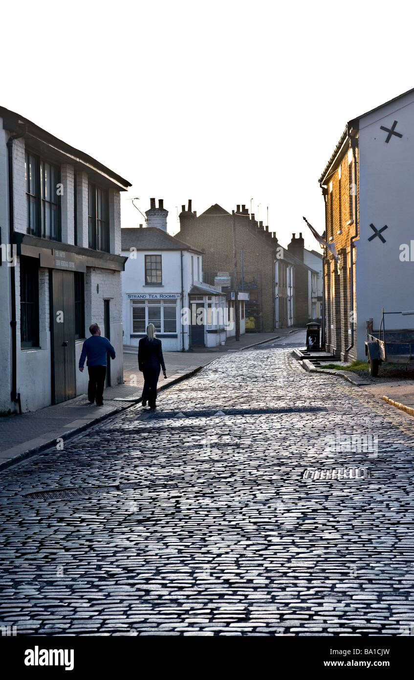 Two people walking along the cobbled street in Leigh on Sea in Essex Stock Photo