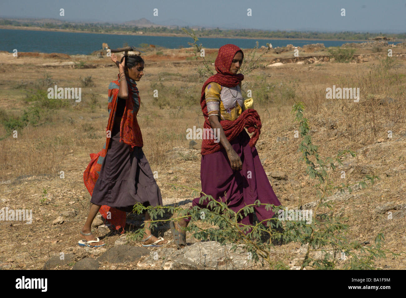 Two Indian women returning from work and carrying axe on head in Gujarat India Stock Photo