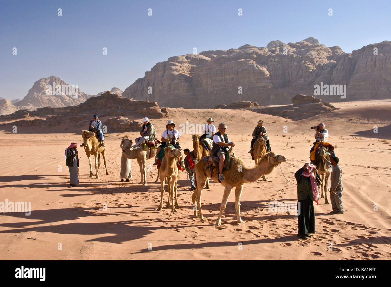 Tourists riding camels in desert, Wadi Rum, Jordan Stock Photo