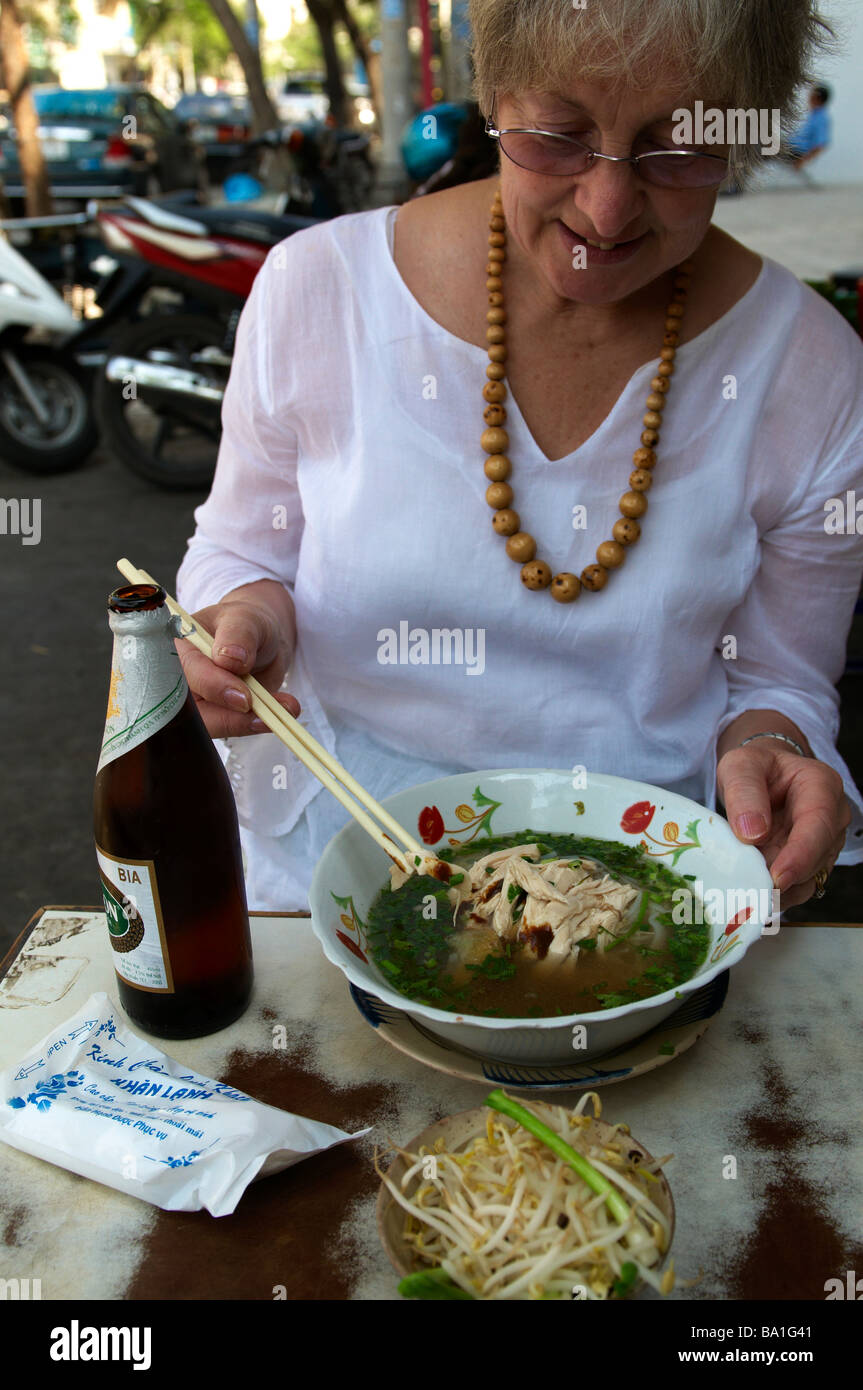 Tourist Enjoying Chicken and Noodle Soup , known as pho,in a Street