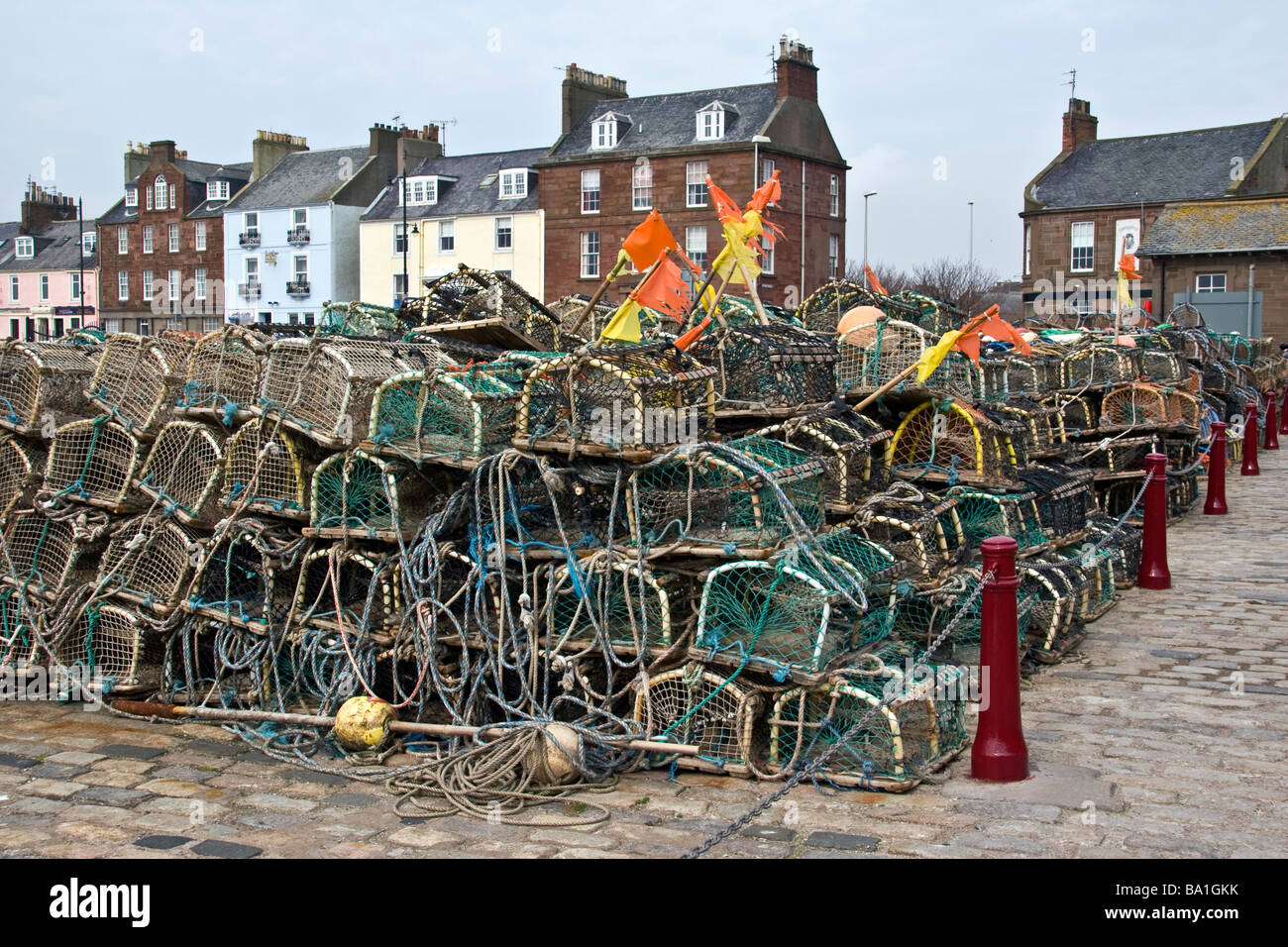 Fishing creels alongside Arbroath harbour and at the quay side and row of colourful harbour houses UK Stock Photo