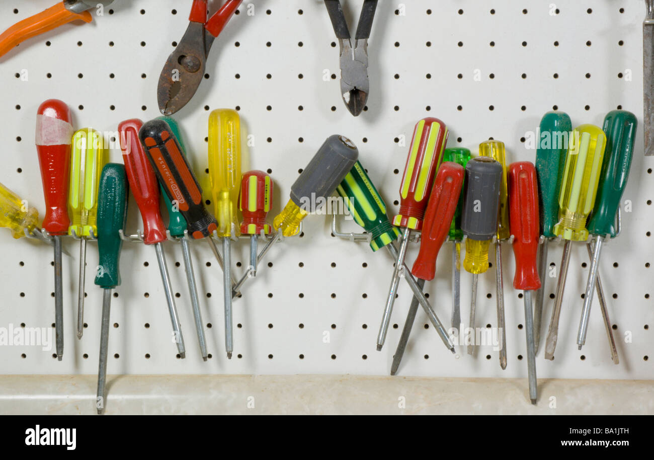 Tools hanging on wall above work bench Stock Photo