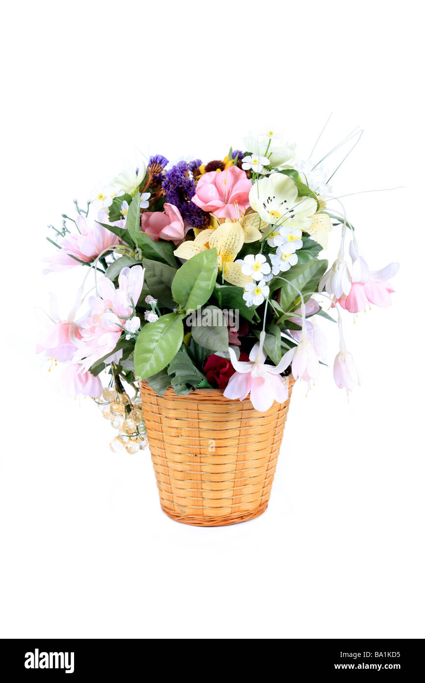 Fake flowers in a whicker plant pot against a white background Stock Photo