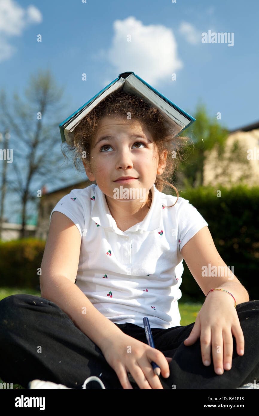 I wish school were over! Little girl with book over her head Stock ...