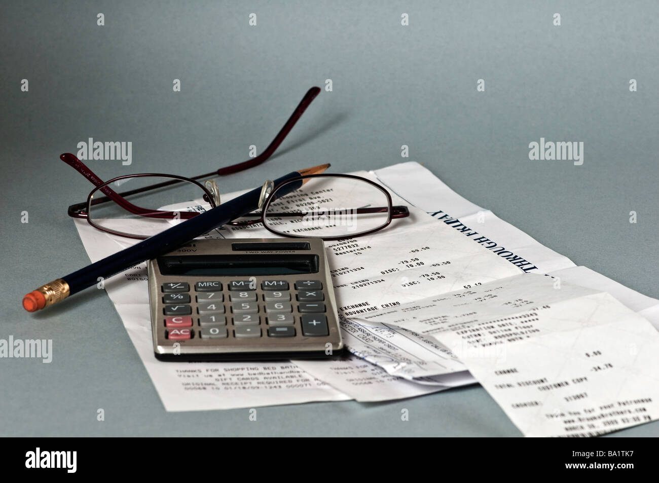 Calculator on top of receipts with pencil and reading glasses Stock Photo