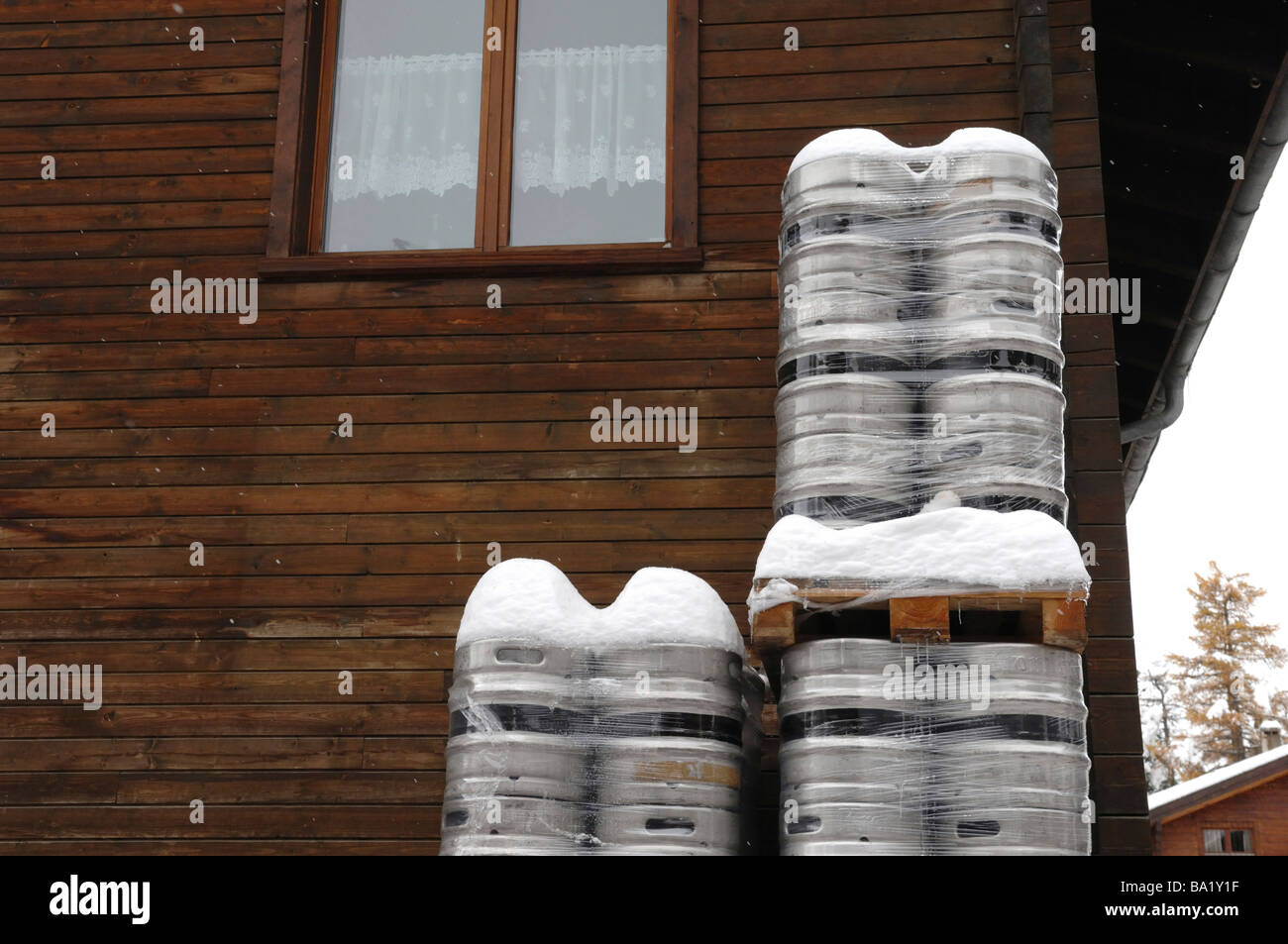 Beer barrels coered in fresh snow outside a traditional wooden bar in the Swiss Alps Stock Photo