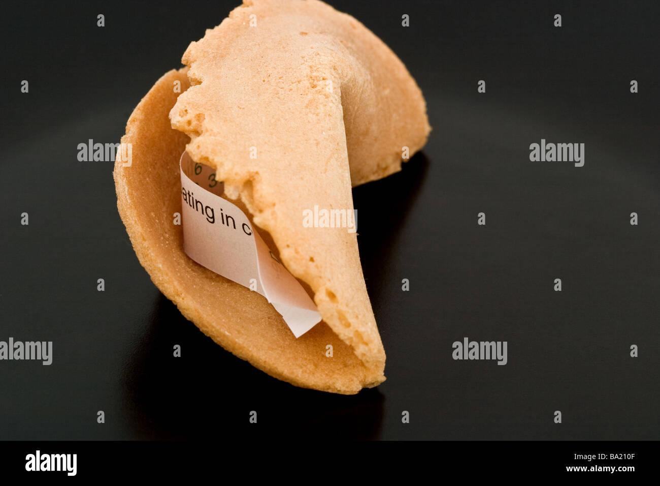 Chinese fortune cookie with a paper fortune message still inside Stock