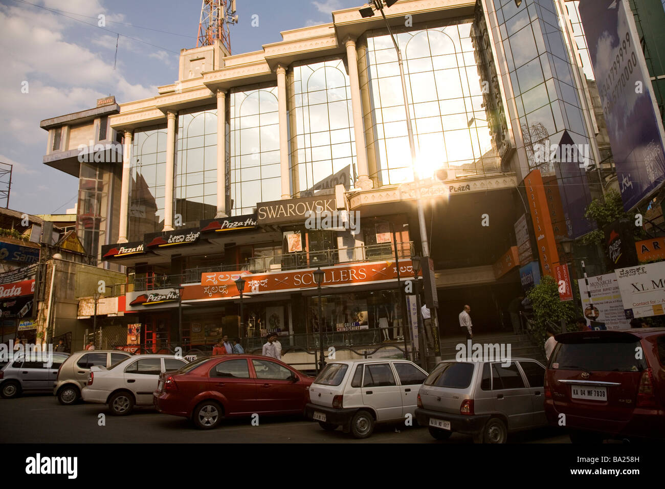 Cars park outside of a shiny, glass fronted building on Brigade Road in