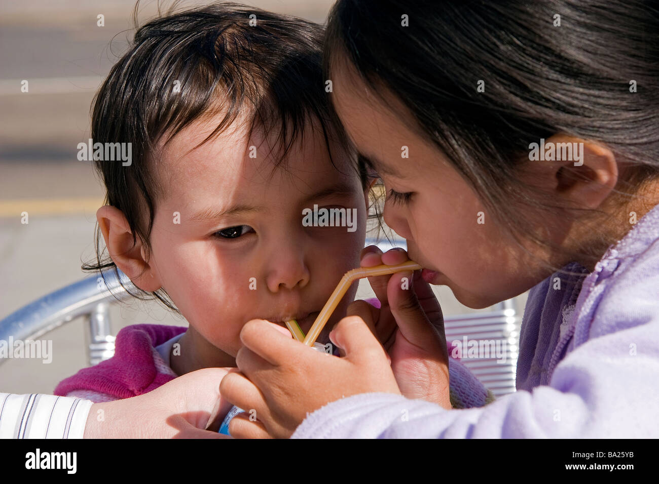 https://c8.alamy.com/comp/BA25YB/two-young-half-thai-sisters-on-their-summer-holidays-drink-from-the-BA25YB.jpg