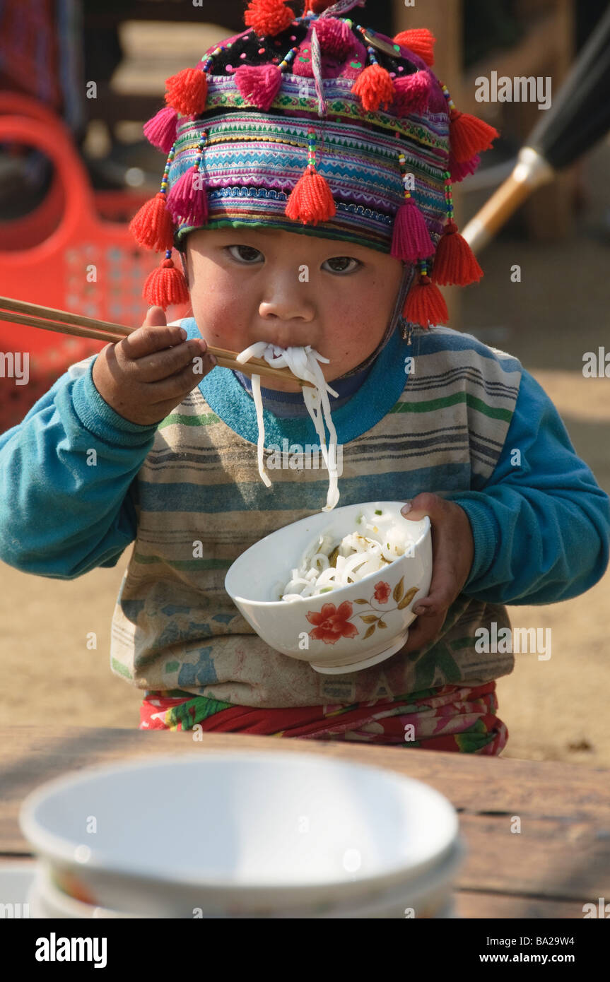 Hmong boy stuffing his face with noodles at market in Tam Duong near Sapa Vietnam Stock Photo