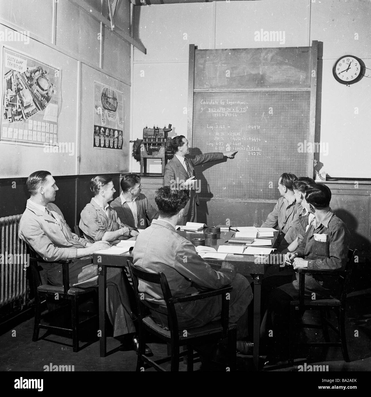 1950s, inside a room, a small group of factory managers sitting around a table, being taught logarithms, by a teacher at a blackboard, England, UK. Stock Photo