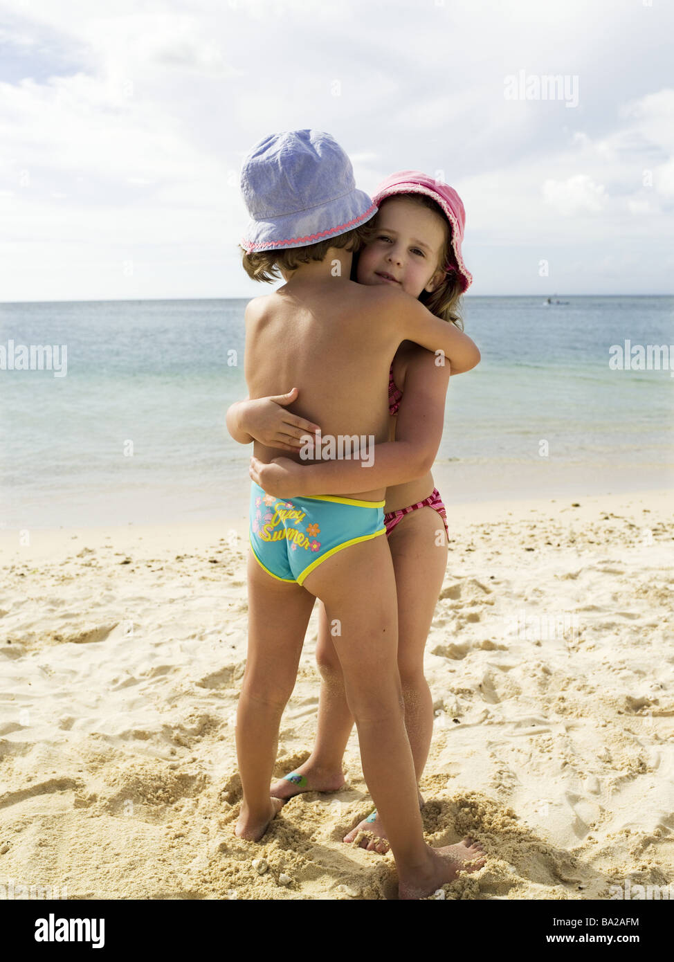 Sandy beach children bath-clothing embrace series beach sand 5-6 years  girls sisters twins friends friendship happily vacation Stock Photo - Alamy