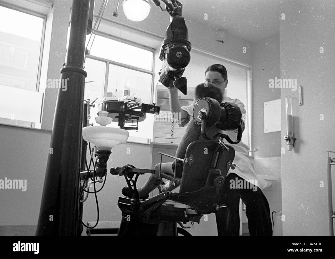 Dental clinic 1950s, a young boy sitting in a chair having his teeth x rayed by a male dentist, England, UK. Stock Photo