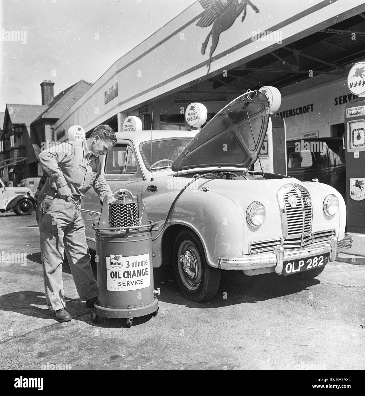 1950s, a uniformed service station attendant giving a car of the era, an oil change at Osterley Motors on the A4 Great West Road London England, UK. Stock Photo