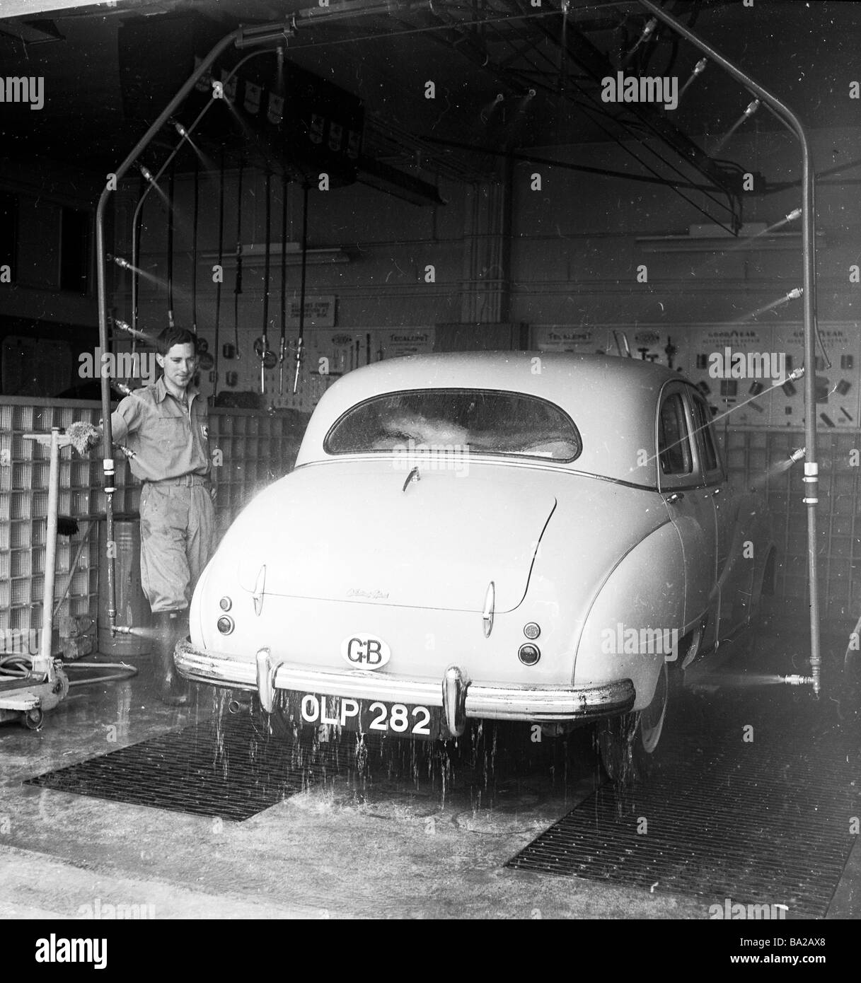 1950s, car wash, a male attendant overseeing an Austin car of the era being washed by a number of jets on a pipe at a  service station, England, UK. Stock Photo