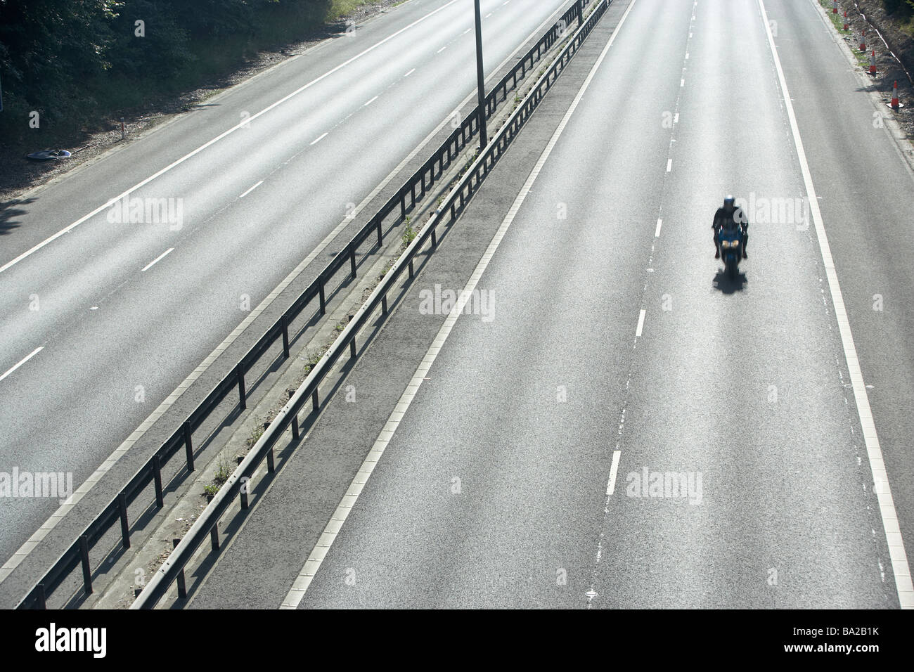 Lone Biker On An Empty Highway Stock Photo