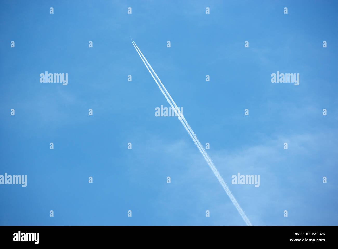 White Condensation Trail From A Jet As It Flies Across A Blue Sky Stock Photo