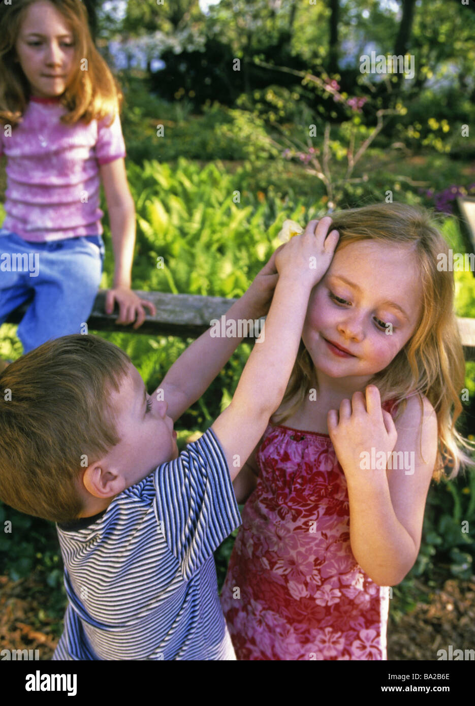Boy puts flower in girl s hair Stock Photo Alamy