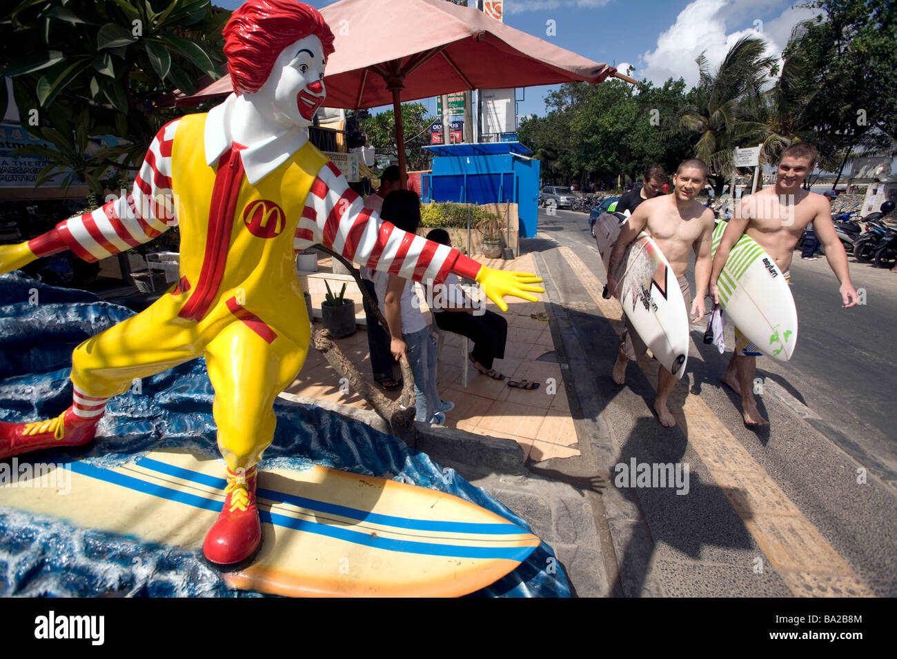 Indonesia, Bali. Kuta. Surfers, McDonalds restaurant, surfing Ronald McDonald statue, surfers. Stock Photo