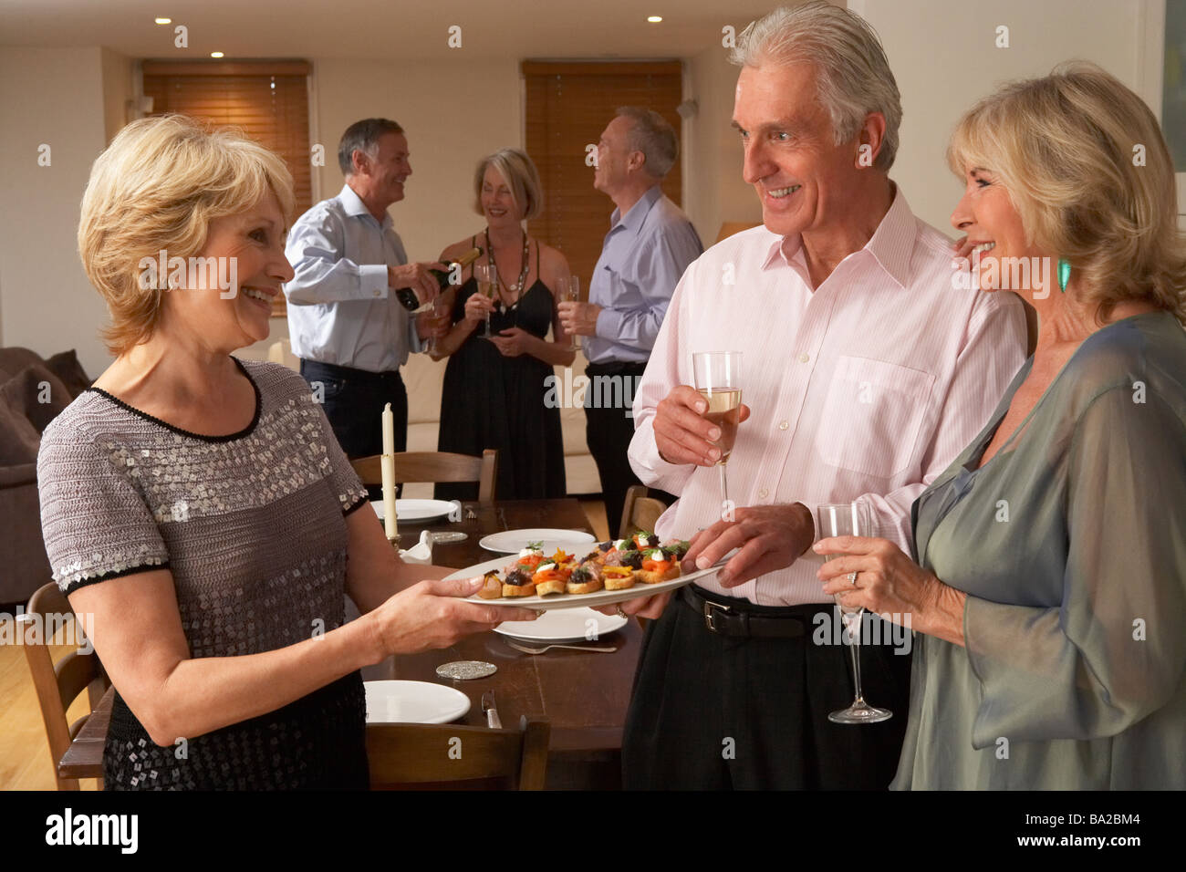 Woman Serving Hors D'oeuvres To Her Guests At A Dinner Party Stock Photo