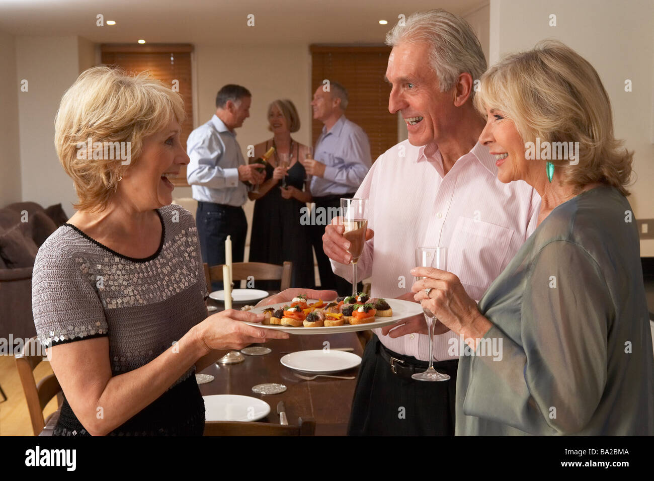 Woman Serving Hors D'oeuvres To Her Guests At A Dinner Party Stock Photo